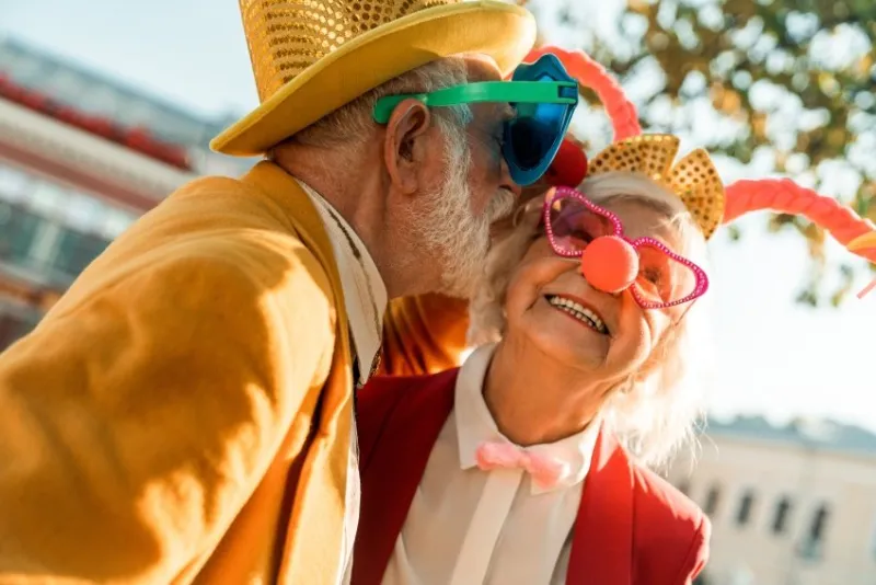 happy elderly couple in clown accessories enjoying a walk stock photo