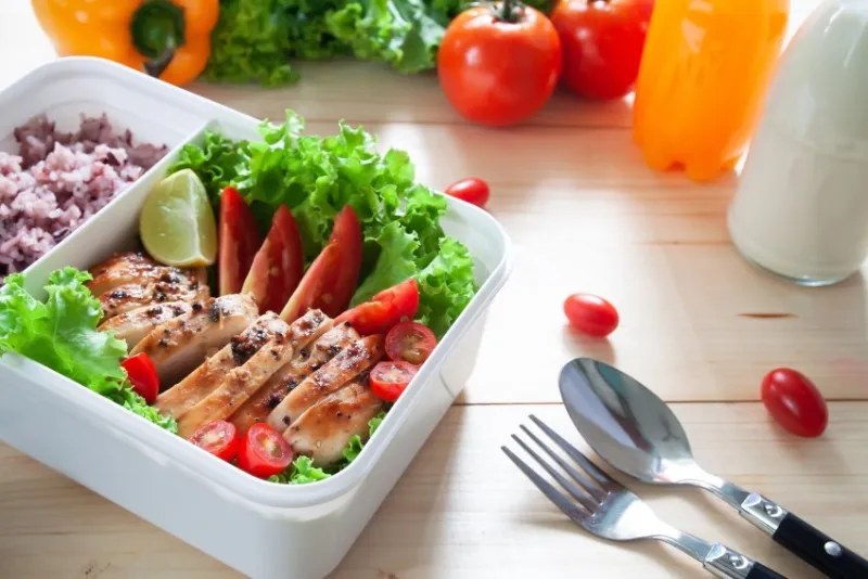 close up of lunch box, grilled chicken breast with lettuce, tomatoes, lime and ricr berry healthy lifestyle