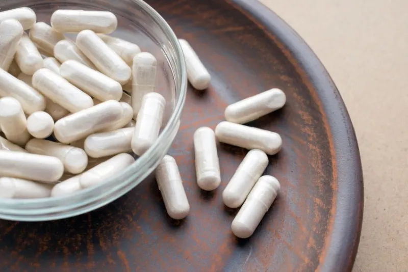 kava kava extract root veg capsules on round clay brown plate herbal supplements with calming relaxation, effect, helps support emotional balance anti stress herbal pills dietary supplement