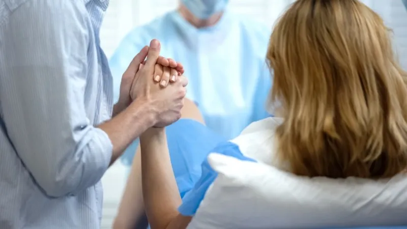 close-up of man holding wife hand for support during pushing to give childbirth