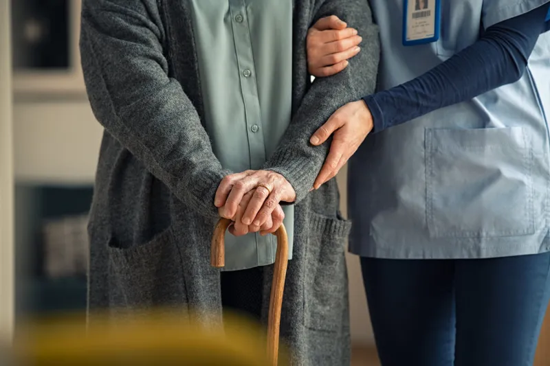 close up hands of caregiver doctor helping old woman at private clinic close up of hands of nurse holding a senior patient with walking stick elder woman using walking cane at nursing home with nurse holding hand for support