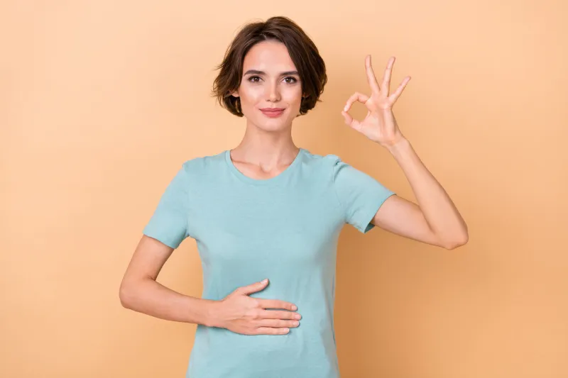photo of young lady arm on belly show fingers okey symbol good promo isolated over beige color background
