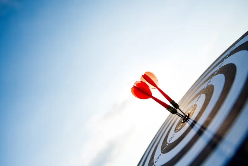 close up shot red darts arrows in the target center on dark blue sky background business target or goal success and winner concept