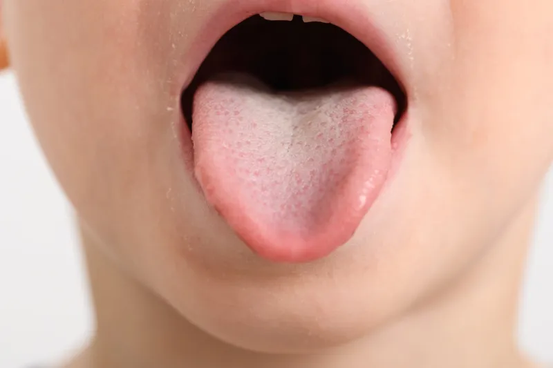 studio shot of little boy's face, sticking out tongue