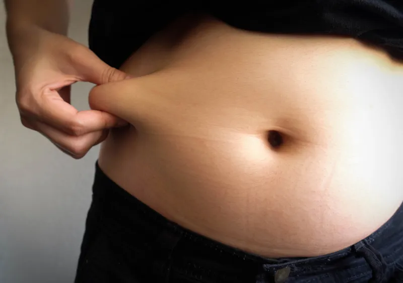 woman hand catching fat body belly paunch , diabetic risk factor