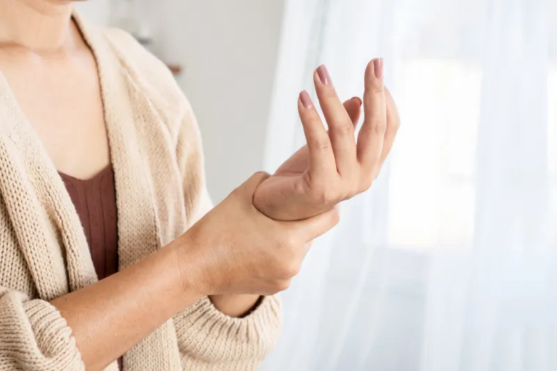 woman suffering from wrist pain, numbness, or carpal tunnel syndrome hand holding her ache joint