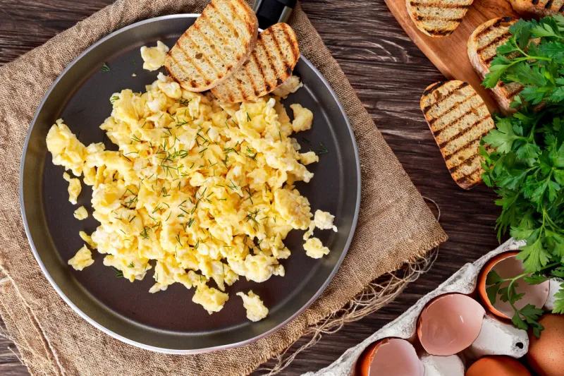 scrambled eggs on pan with grilled toast