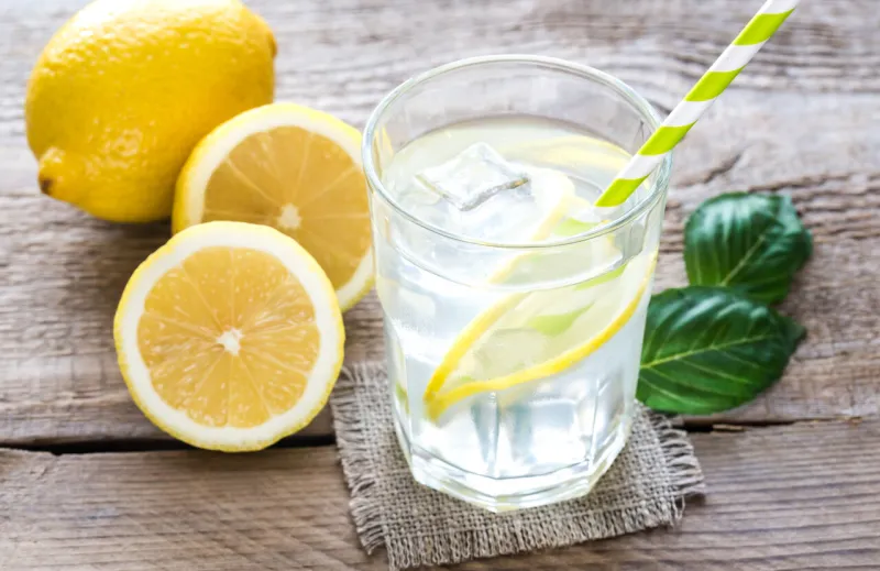 glass of water with fresh lemon juice on the wooden table