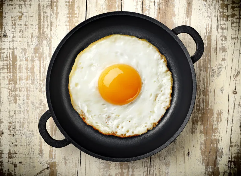 fried egg in black iron frypan on wooden background