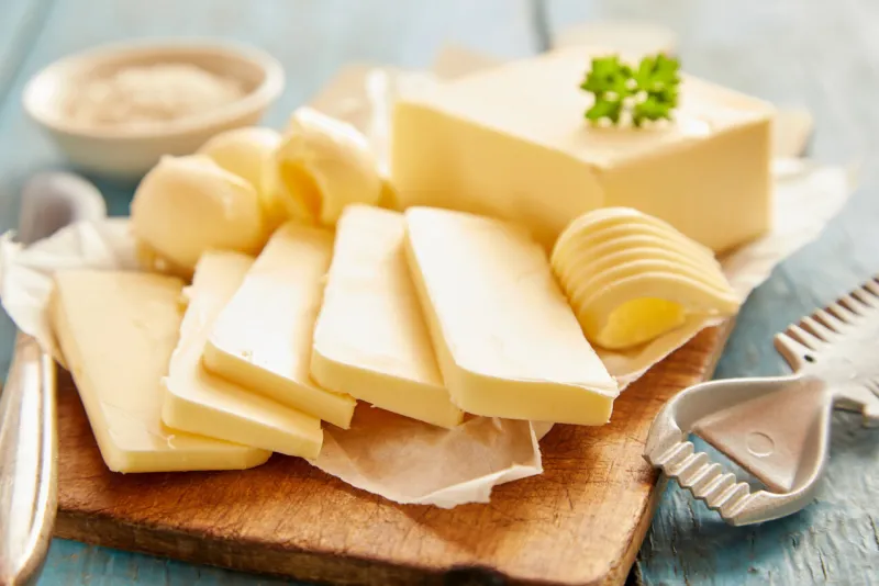 close up view of butter sliced on cutting board against blue wooden background