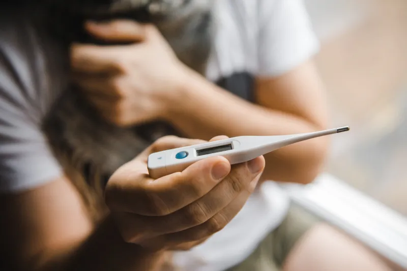 man feeling bad lying in the bed and looking the thermometer , main focus on the thermometer