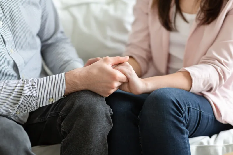 close up of married couple holding hands during family therapy, support and reconciliation concept