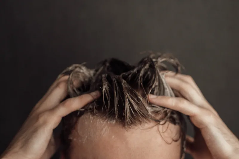 a man washes his hair  hands and wet hair in shampoo foam
