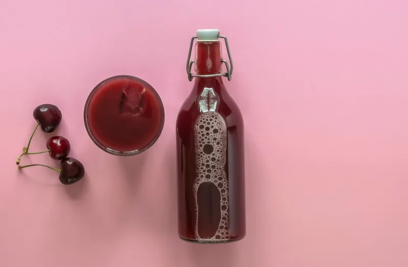 summer cherry juice in a glass and bottle with ripe berries top view, copy space for text the concept of cold refreshing drink morse or kompot