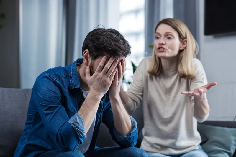 family conflict, quarrel, misunderstanding the woman shouts at her husband, in despair, crying requires explanation the man listens, covering his face with his hands sitting on the couch at home
