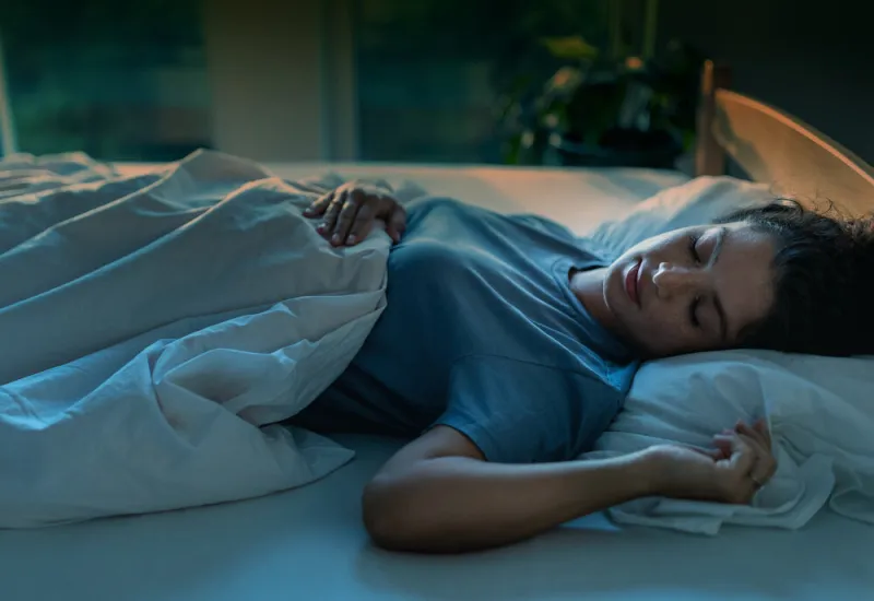 young pretty woman sleeping in bed in night with street light coming from windows