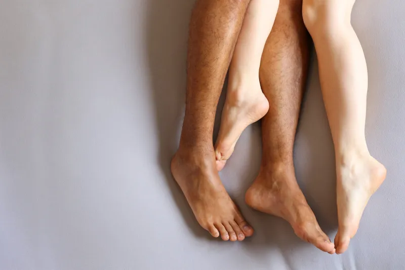 legs of interracial couple in bed - copy space