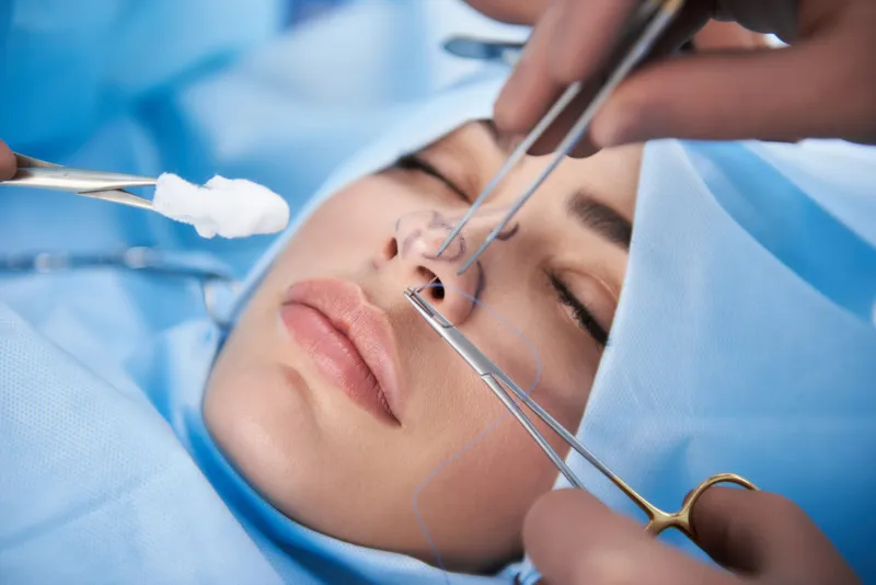 close up photo of lady with nice lips in operating room doctor in gloves holding medical instrument during rhinoplasty