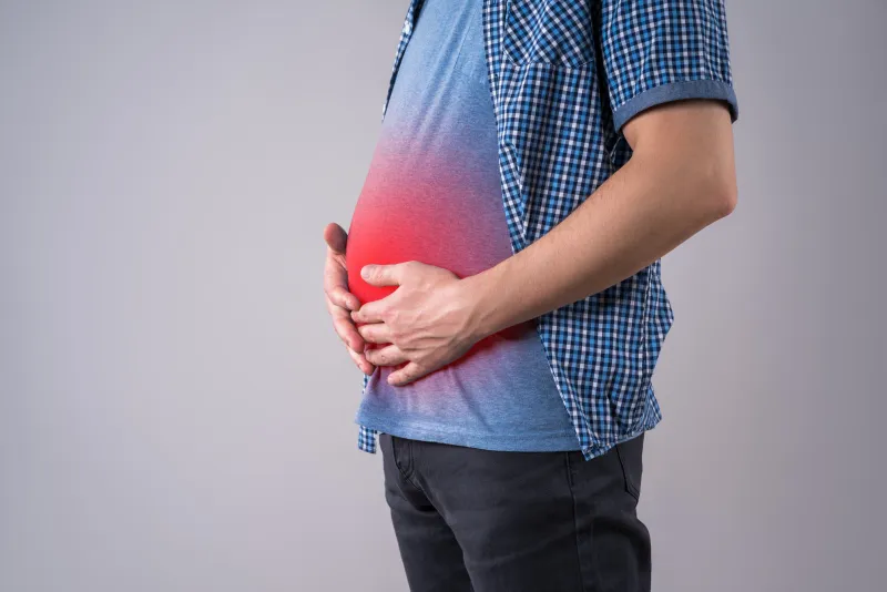 fat man with bloating and abdominal pain, overweight male body on gray background, studio shot