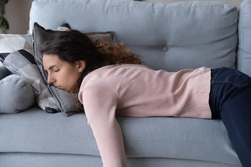 tired unmotivated young woman falls asleep on cozy couch indoors, having no energy after hard working day exhausted caucasian lady napping on comfortable sofa in living room, fatigue concept