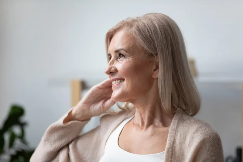 close up of positive elderly female pensioner sit relax at home look in distance window dreaming or visualizing, smiling mature woman grandmother lost in thoughts remember good old days, happy life