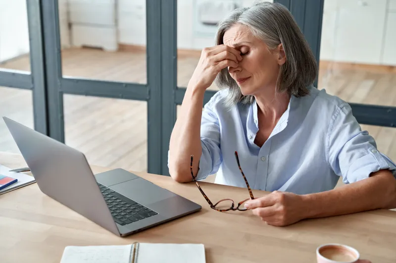 overworked tired older lady holding glasses feeling headache, having eyesight problem after computer work stressed mature senior business woman suffering from fatigue rubbing dry eyes at workplace