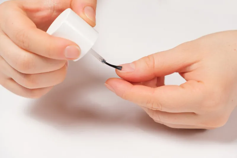 applying a transparent varnish, degreaser to the nails close-up on a white background