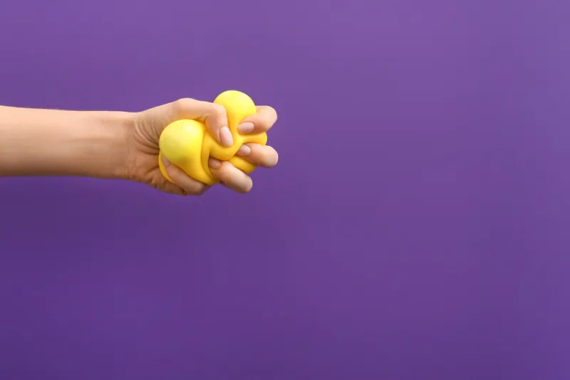 hand squeezing stress ball on color background