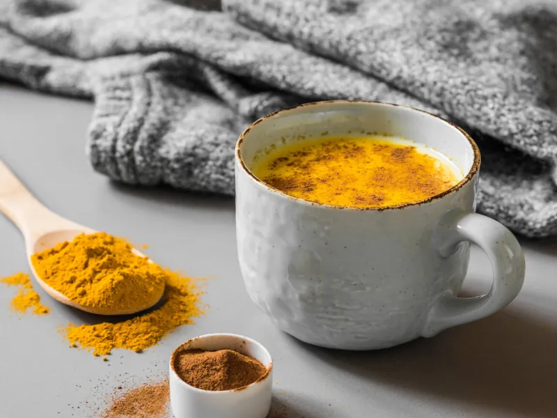 turmeric latte with milk and cinnamon elixir of health and vivacity traditional healthy indian detox drink grey background