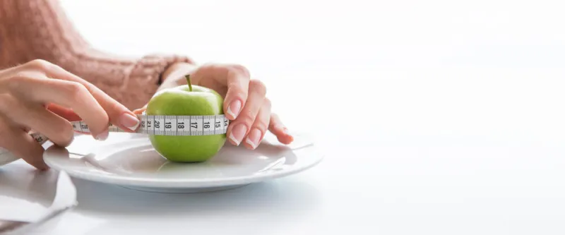 woman measures the circumference of the apple with tape measure