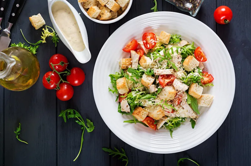 healthy grilled chicken caesar salad with tomatoes, cheese and croutons north american cuisine top view