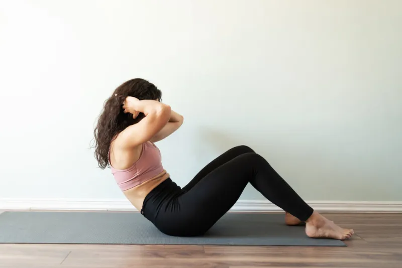 profile view of a fit young woman with curly hair doing sit up exercises for her home workout