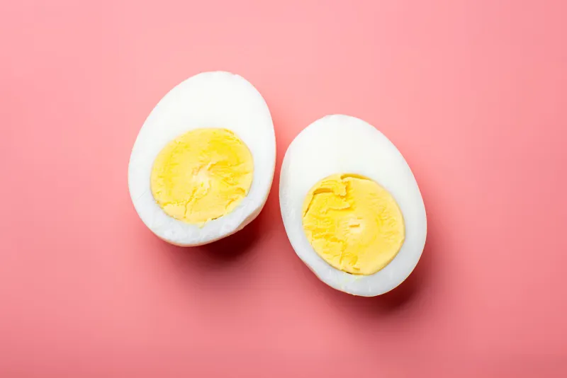 sliced boiled chicken egg on a pink background