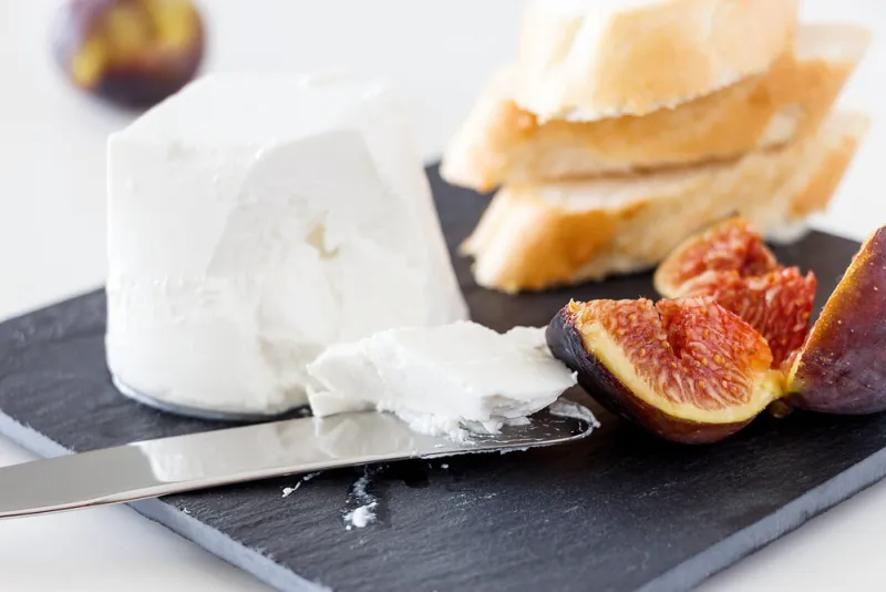 goat cheese, fresh ripe fruit figs and freshly baked french baguette light background