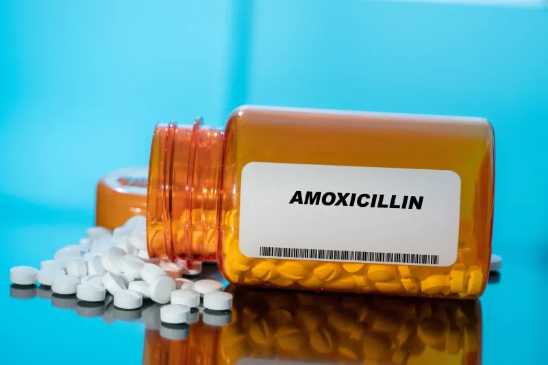 amoxicillin white medical pills and tablets spilling out of a drug bottle macro top down view with copy space