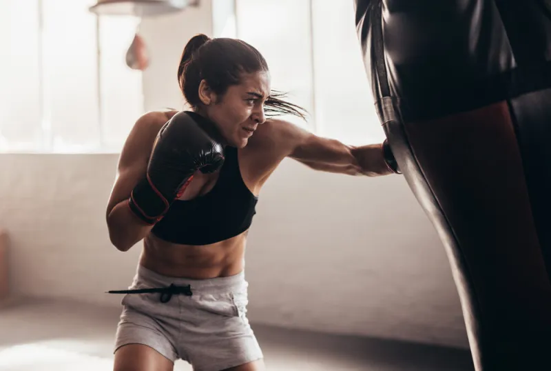 female boxer hitting a huge punching bag at a boxing studio woman boxer training hard