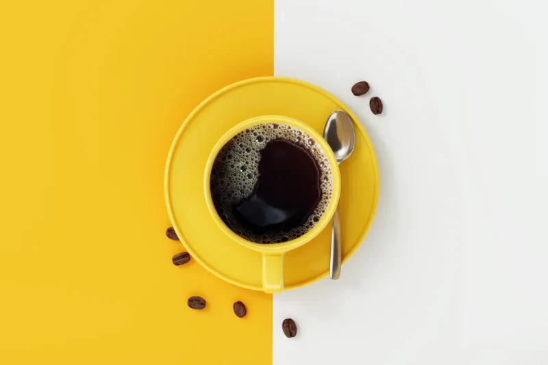 top view of coffee cup on yellow and white background