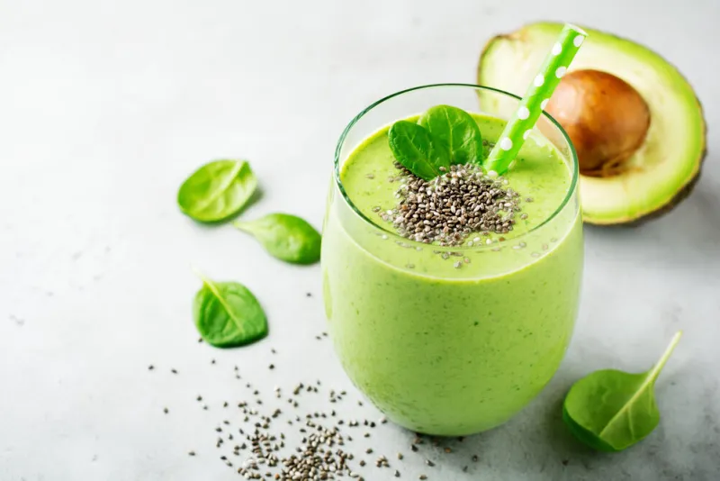 vegetarian healthy green smoothie from avocado, spinach leaves, apple and chia seeds on gray concrete background selective focus space for text