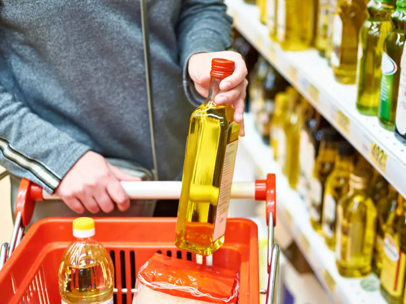 bottle of olive oil in the hand of the buyer at the grocery store