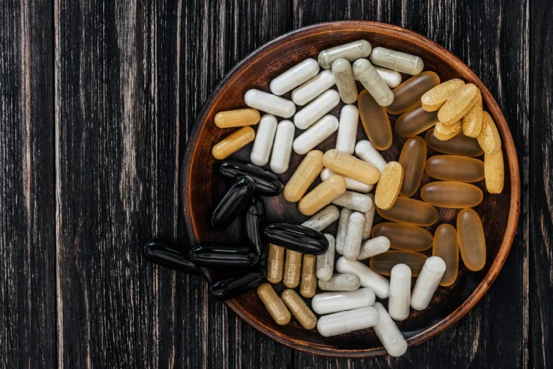 multivitamin pills on a clay plate, on a vintage wooden table