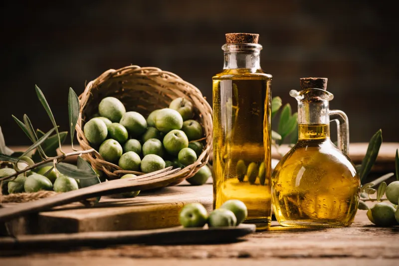 olive oil with fresh olives on rustic wood close up