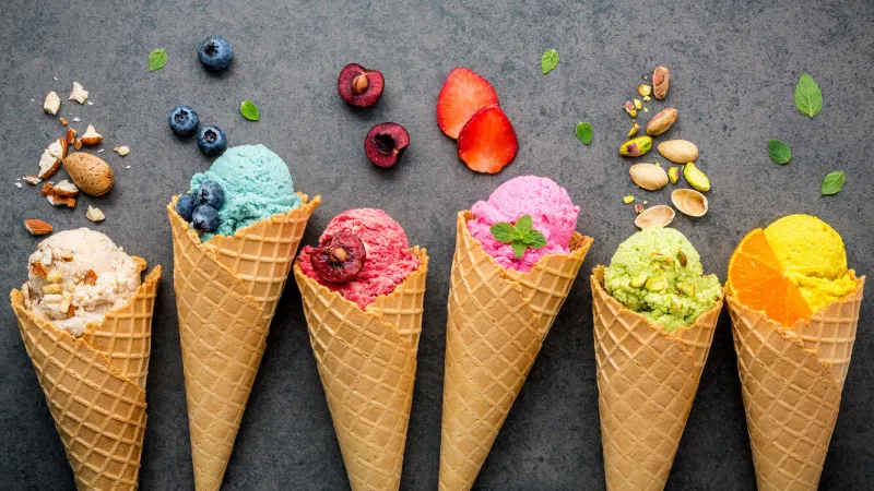 various of ice cream flavor in cones blueberry ,strawberry ,pistachio ,almond ,orange and cherry setup on dark stone background summer and sweet menu concept