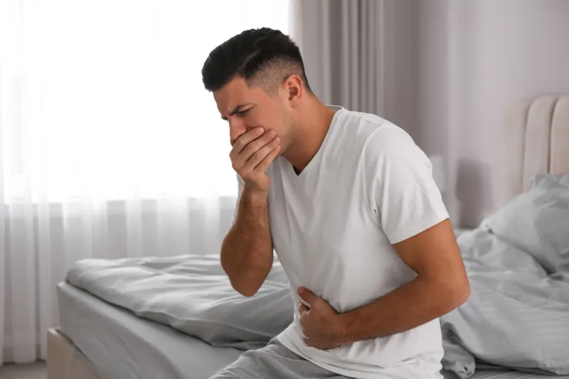 man suffering from nausea on bed at home food poisoning