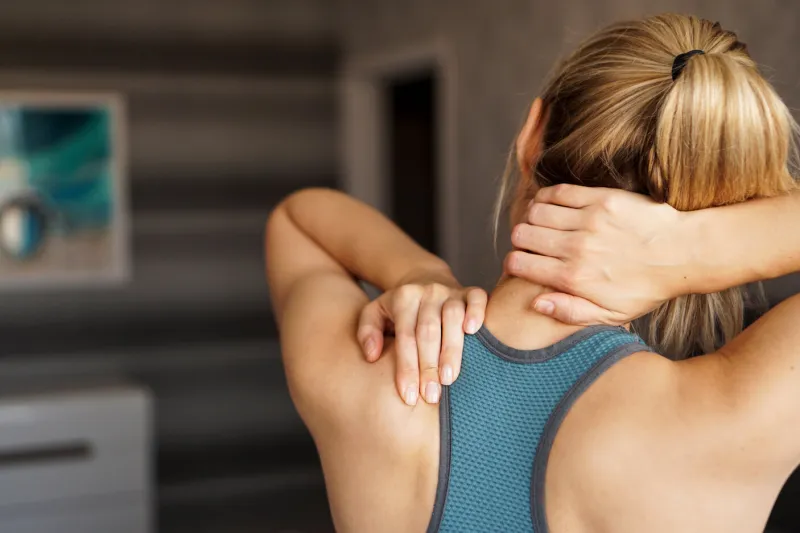 sports injury concept athletic girl feeling pain in her neck against blurred background pain after home workout