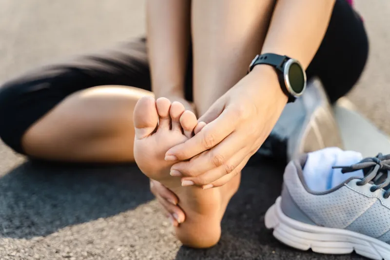 running injury leg accident- sport woman runner hurting holding painful sprained ankle in pain female athlete with joint or muscle soreness and problem feeling ache in her lower body