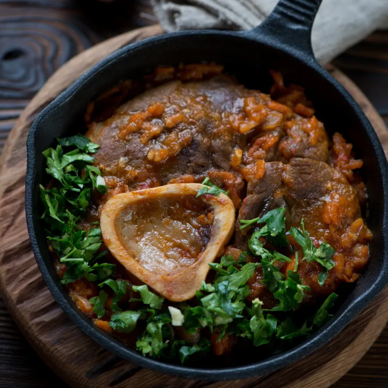close-up of ossobuco with gremolata in a frying pan, studio shot