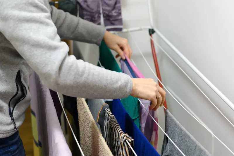 woman hangs laundry to dry at home