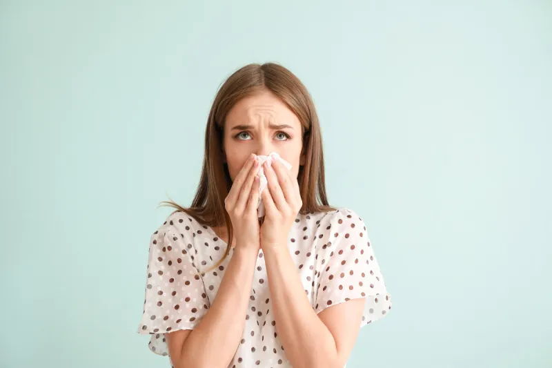 young woman suffering from allergy on light background