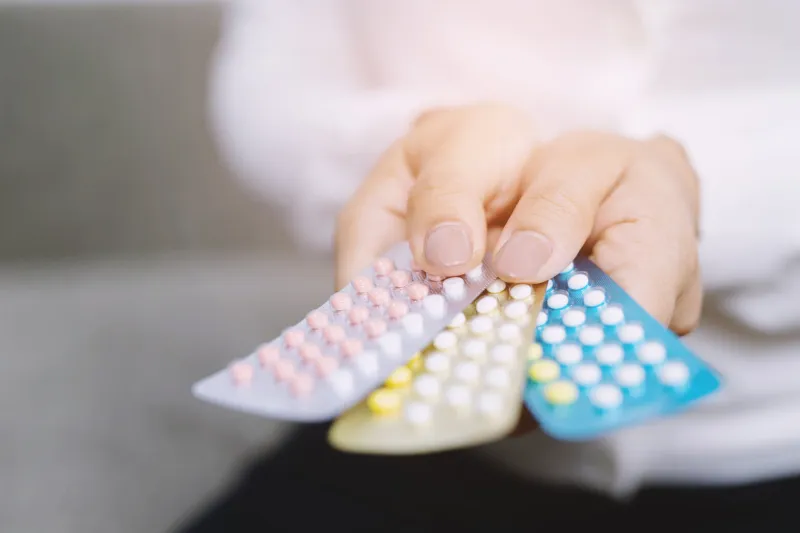 close up hand contraceptive pill on with colorful pills strips