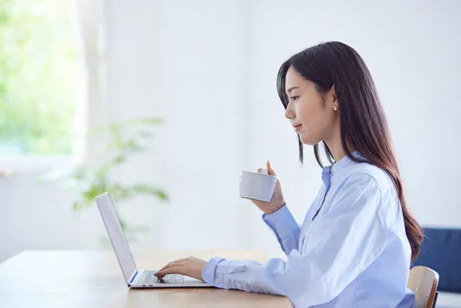 リビングでパソコンを操作する女性20代の日本人女性の夏のイメージ